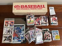 Fleer Baseball logo sticker & trading cards box, loose hockey cards and sealed Topps box on table