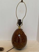 Full view of lamp showing teardrop-shaped glass base, black socket and harp against white background.