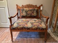 Front view of carved wooden frame and tapestry upholstery