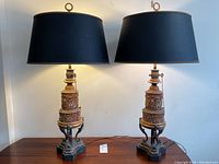 Both lamps side by side on a wooden surface showing full height and scale with shades on