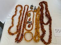 Five amber necklaces, one amber bracelet, two silver brooches and three amber pendants arranged on white cloth