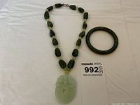 Overview of necklace with carved jade pendant and jade bangle.