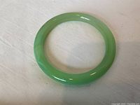 Top-down view of pale green jade bangle on white surface