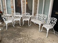 Overview of four armchairs and one loveseat bench arranged on patio