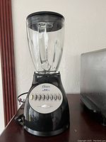 Front view of Oster 4345 black blender with glass container on top, showing control panel and power switch.