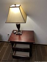 Photo of a dark cherry wood coffee table or nightstand with two drawers, with a lamp placed on top.