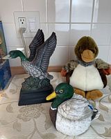Photo of two duck statues and a duck plush arranged on a kitchen countertop with tile backsplash