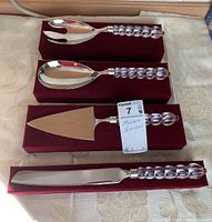 Four Mikasa serving utensils displayed with velvet cases. Includes a serving fork, serving spoon, cake server, and knife, each with Austrian crystal handles.