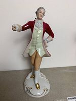 Front view of the Royal Dux porcelain figure showing detailed hand-painting, red coat, cream waistcoat, and base decoration.
