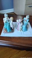 Side view photo showing both figurines placed on a wooden surface, highlighting their size and colors