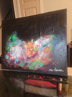 Angled photo of the painting showing the colorful abstract design and signature.