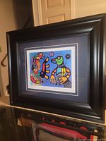 Full view of the professionally framed and matted print showing colorful abstract figures, acrylic or giclée print in a dark wood frame with double mat.