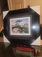 Framed art piece showing the full front with protective corner covers on the frame.