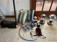 Photo showing two Arden Outdoor striped pillows, two metal lanterns, ropes, and small outdoor accessories scattered on the floor.