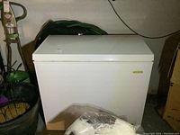 Front view of white chest freezer showing smooth finish and nearby items.