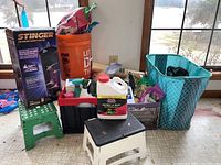 Wide view showing all gardening supplies including Miracle Gro products, step stools, garden chemicals, and insect killer in totes and bags