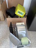 Various hydroponic and grow light system components including yellow container and black iDoo unit in cardboard box, clear plastic tub holding metal and plastic parts, tubing.