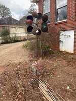 Full view of two lawn wind catchers outside next to a brick house on bare soil, showing height and condition of both items.
