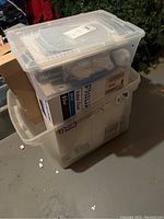 Clear plastic storage container holding multiple boxes of lightbulbs including Phillips and others.