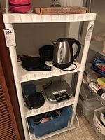 White plastic storage shelf with several kitchen items on shelves, front view