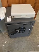 Similar overall view showing the white locking box and grey safe below