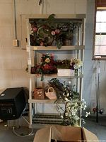 Full front view of item with artificial flowers on each shelf, basement setting.