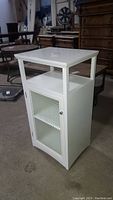 White wooden bathroom cabinet with open upper shelf and closed lower compartment with textured glass door showing two shelves inside, front side view