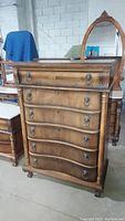 Front view of the high vintage dresser showing six drawers with lion head pulls and claw feet, wood finish, minor scratches.