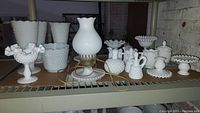 Shelf display showing all 18 hobnail milk glass pieces including lamps, vases, candy dishes, cruets, sugar & creamers, bud vase, and candle holders