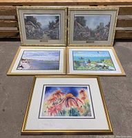 Five framed art prints arranged outdoors showing landscapes and floral themes.