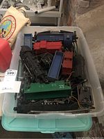 Bin of various toy trains, mostly Lionel brand, including blue and red locomotives and various railcars.