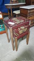 Side view of both nesting tables stacked, showing floral design and drawer on smaller table.