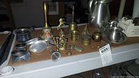 Full view of lot on cardboard surface showing pewter, brass, and silverplate items arranged across two boxes.