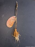 Photo of antique muskie fishing lure with rusted metal blade, wire, swivel, and feather bait attached.