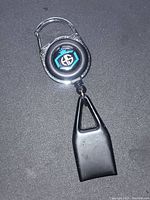 Front view of clip on lighter leash showing circular retractable body with logo and black plastic lighter holder.