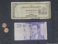 Photo showing the front side of Japanese Government 10 Pesos note, 20 Dirhams Bank Al-Maghrib note with portrait, and two pennies.