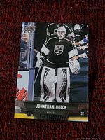 Photo of a Jonathan Quick hockey card showing the player in full goalie gear for the LA Kings on the ice.
