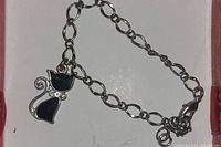 Silver-tone chain bracelet with a black enamel cat charm and rhinestone accents on a white background.