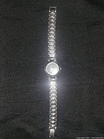 Full length image of silver-tone stainless steel ladies wristwatch showing linked band and round face.