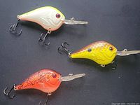 Photo of three 3-inch fishing crank baits in white/yellow, orange, and yellow/brown colors with treble hooks and diving lips.
