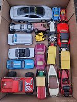 Top view of a box containing a variety of vintage die cast cars and trucks arranged tightly together.