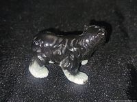 Porcelain bear figurine standing on a black textured surface showing front and side profile.