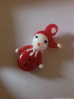 Santa pendant made from milk glass and ruby red glass, showing front details and loop for hanging.