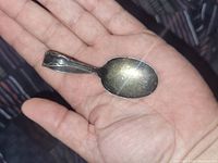 Silver plated antique baby spoon resting in a hand, showing the front and bowl of the spoon.
