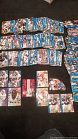 Photo showing multiple stacks of vintage NFL football cards laid out on a dark floor, including visible Dallas Cowboys player cards.