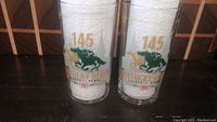 Two clear Kentucky Derby souvenir glasses side by side, showing front horse racing graphic with '145' and event text