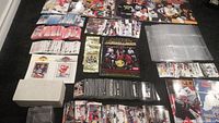 Top-down view showing large assortment of sorted hockey cards, plastic card sleeves, coin packs, price guides, and photo inserts organized on dark surface.