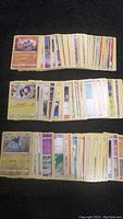 Three laid out stacks of various Pokemon cards showing card artwork and backs in typical trading card size and design.
