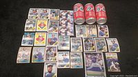 Photo showing an assortment of Toronto Blue Jays baseball cards laid out on a black surface including players Roberto Alomar, Joe Carter (x3), and Roger Clemens