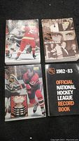 Four NHL guide books from different seasons shown together on a black background